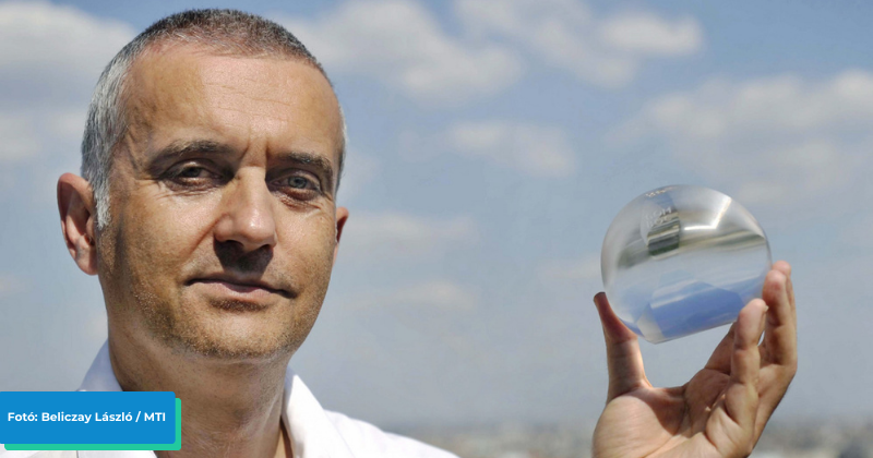 A képen Domokos Gábor, a Gömböc és a Bille felfedező csapatának egyik tagja látható, amint kezében tart egy átlátszó plexiüveg Gömböcöt.