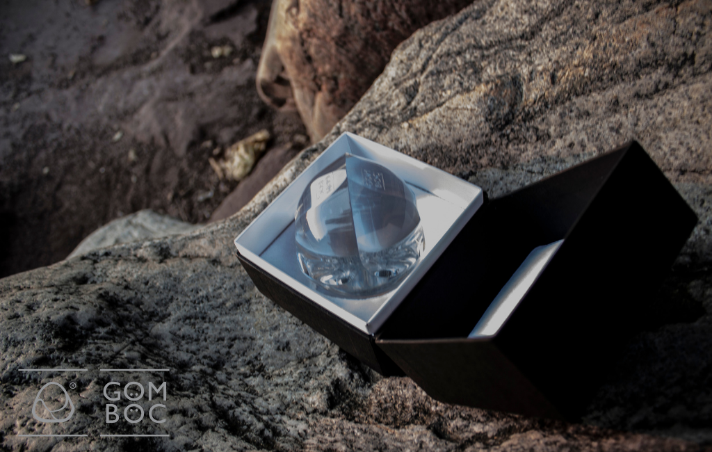 A képen egy Gömböc látható kinyitott díszdobozban egy sziklára helyezve.